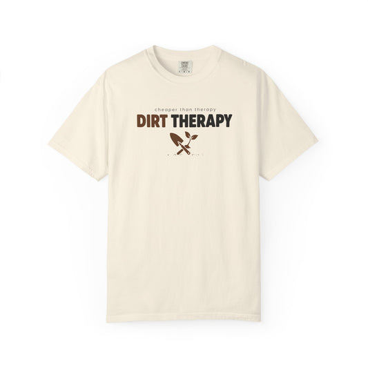 An ivory short-sleeve crewneck t-shirt with a graphic on the chest that reads 'DIRT THERAPY' in brown and black, with a small crossed shovel and plant icon below it, displayed on a clean white background.