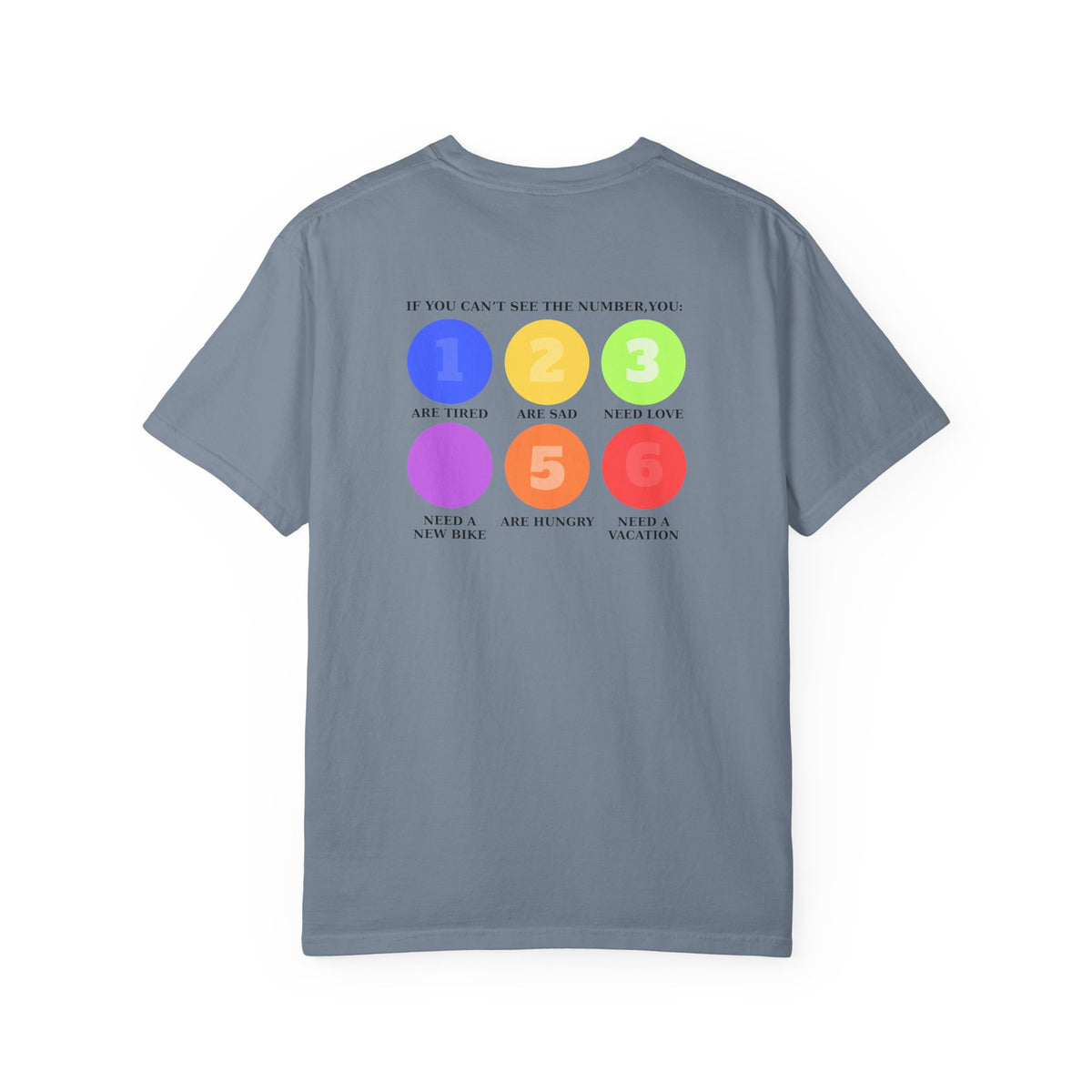 A stone blue green short-sleeve t-shirt with a colorful graphic on the back. The graphic features six colored circles (blue, yellow, green, purple, orange, red) numbered 1 through 6, with text reading 'IF YOU CAN'T SEE THE NUMBER, YOU: 1 Are Tired 2 Are sad 3 Need Love 4 Need a new bike 5 Are hungry 6 Need a vacation'