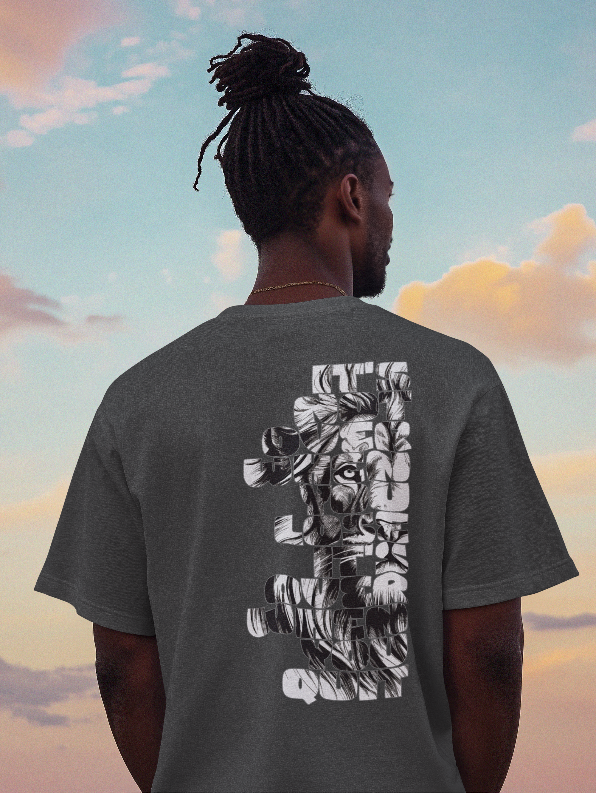A man viewed from behind wearing a dark gray t-shirt with a large white graphic print of a lion on the back, set against a sunset sky background.