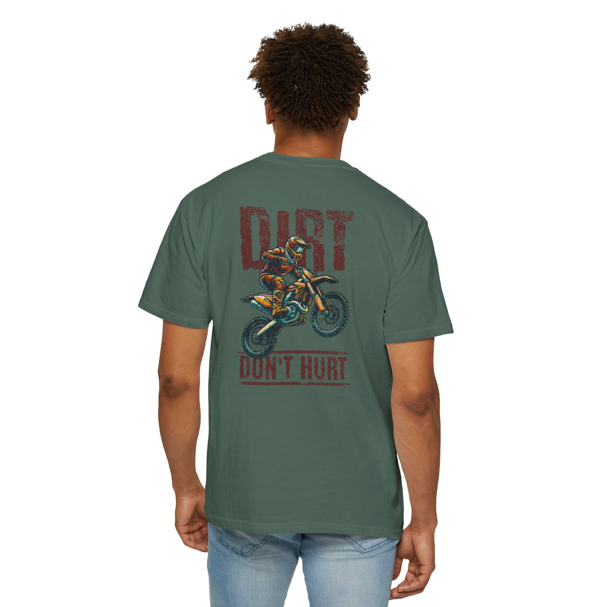 A man viewed from the back wearing a sage green t-shirt with a motocross graphic and the text 'DIRT DON'T HURT' printed on the back, paired with light wash blue jeans against a plain white background.