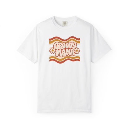A white short-sleeve crewneck t-shirt featuring a retro 1970s-style graphic on the chest with wavy orange and yellow stripes, the text 'GROOVY MAMA' in cream bubble letters, and two small orange flowers, displayed on a clean white background.