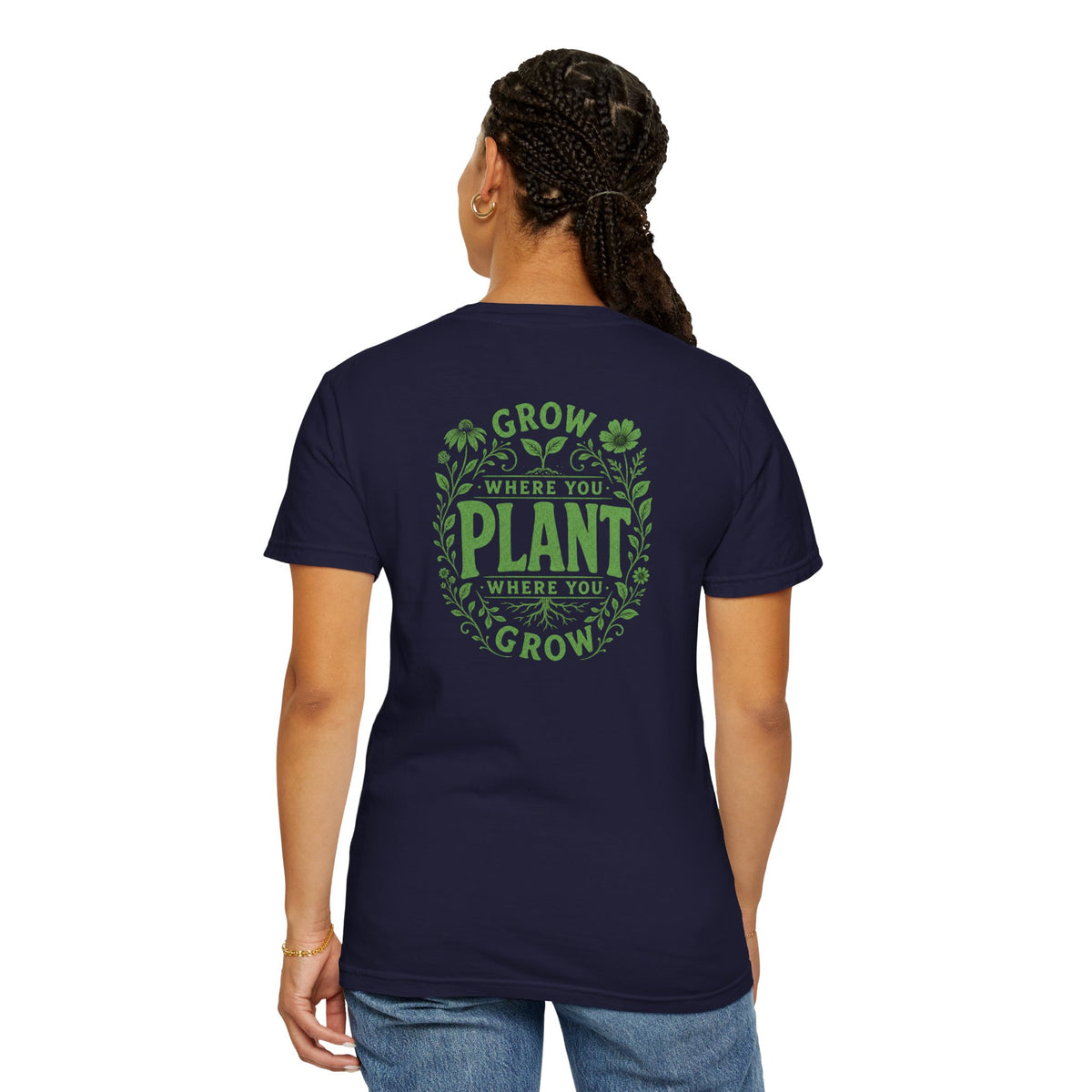 A woman wearing a navy blue short-sleeve t-shirt with a green graphic on the back reading 'GROW WHERE YOU PLANT WHERE YOU GROW' surrounded by leaves and clovers, shown against a plain white background.