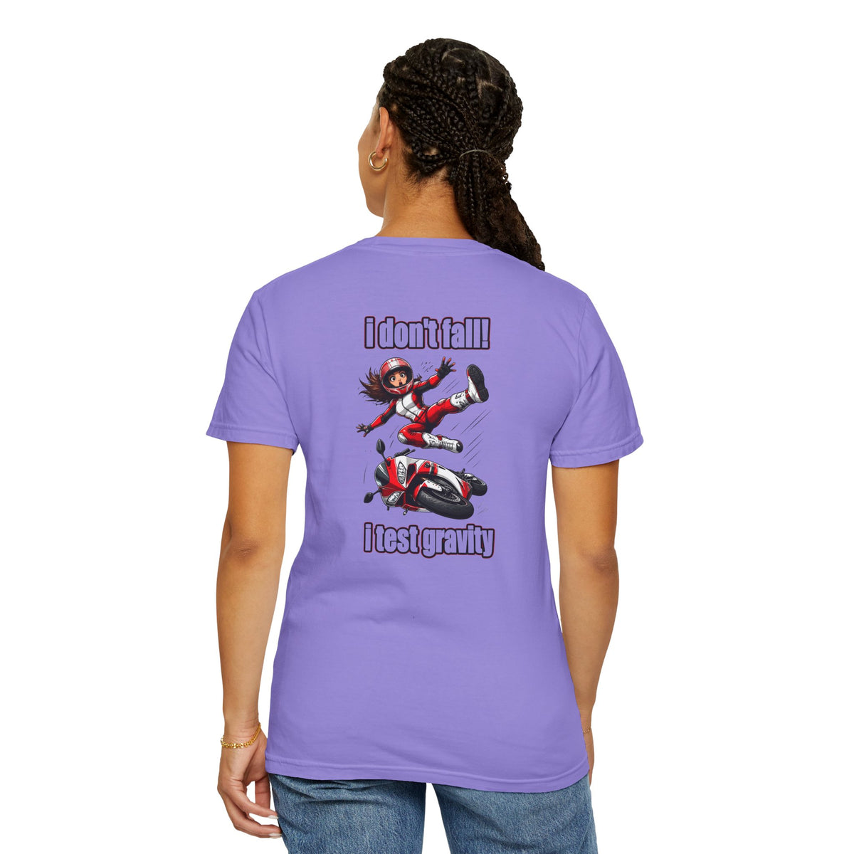 A woman shown from the back wearing a lavender purple t-shirt with a graphic of a girl jumping over a scooter and the text 'I don't fall! I test gravity'.