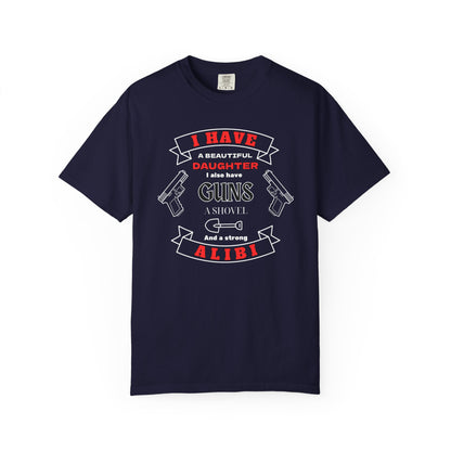 A navy blue short-sleeve crewneck t-shirt with a graphic print on the front. The graphic features the text 'I have a beautiful daughter,i also have guns, a shovel and a strong alibi' in black and red lettering, accompanied by illustrations of two pistols and a shovel.