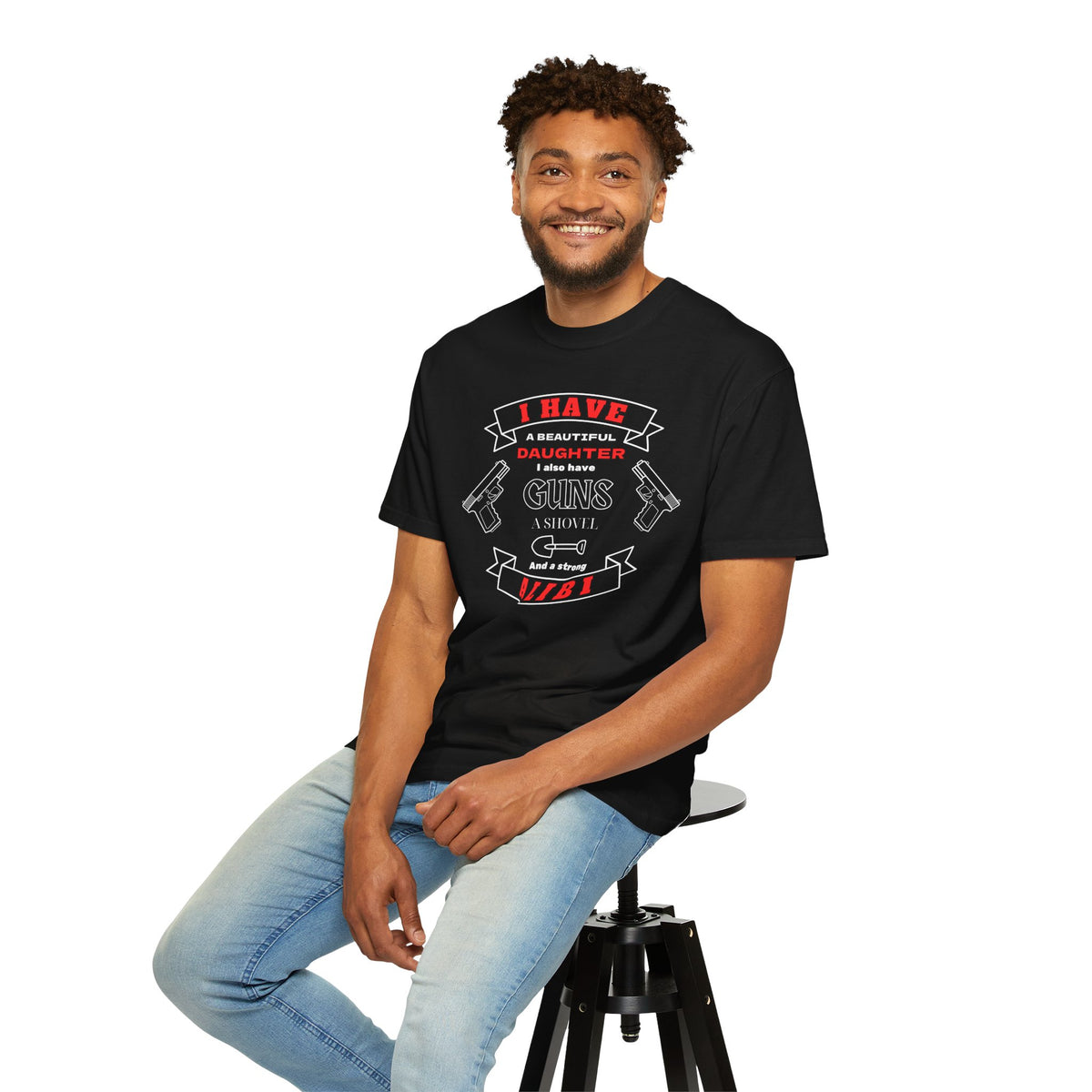 A man wearing a black short-sleeve crewneck t-shirt with a graphic print on the front. The graphic features the text 'I have a beautiful daughter,i also have guns, a shovel and a strong alibi' in black and red lettering, accompanied by illustrations of two pistols and a shovel.