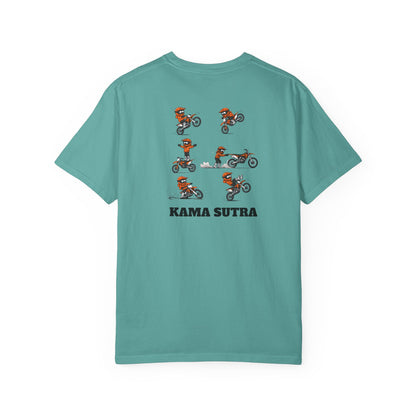 A teal short-sleeve t-shirt with a graphic print of a motocross rider in an orange and white KTM suit performing a jump, with the text 'KAMA SUTRA' printed below in black.