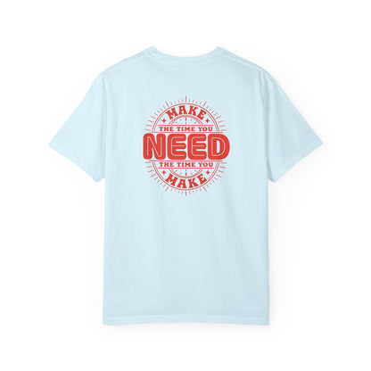 A light blue short-sleeve t-shirt shown from the back, featuring a red circular graphic print with the text 'MAKE THE TIME YOU NEED' in a distressed retro style.