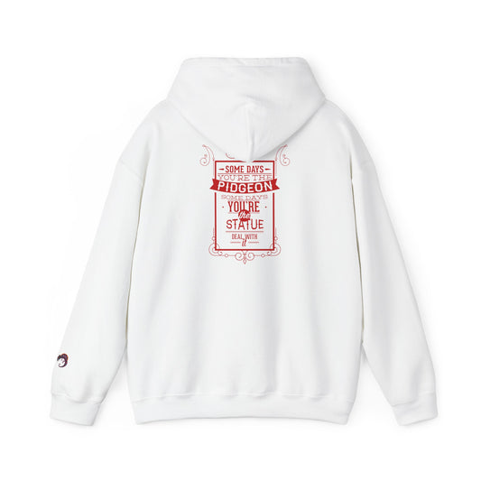 White hoodie with a red graphic print on the back featuring the text 'SOME DAYS YOU'RE THE PIDGEON SOME DAYS YOU'RE THE STATUE DEAL WITH IT' in a vintage-style border design.