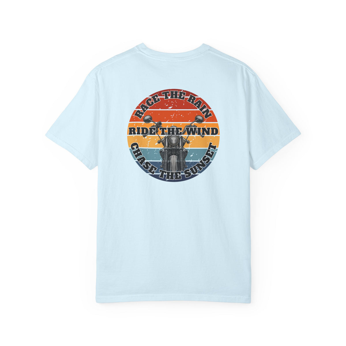 A light blue short-sleeve crewneck t-shirt with a retro circular graphic on the chest. The graphic features a motorcycle silhouette and the text 'RACE THE RAIN', 'RIDE THE WIND', and 'CHASE THE SUNSET' in a distressed sunset color palette of orange, yellow, and blue.