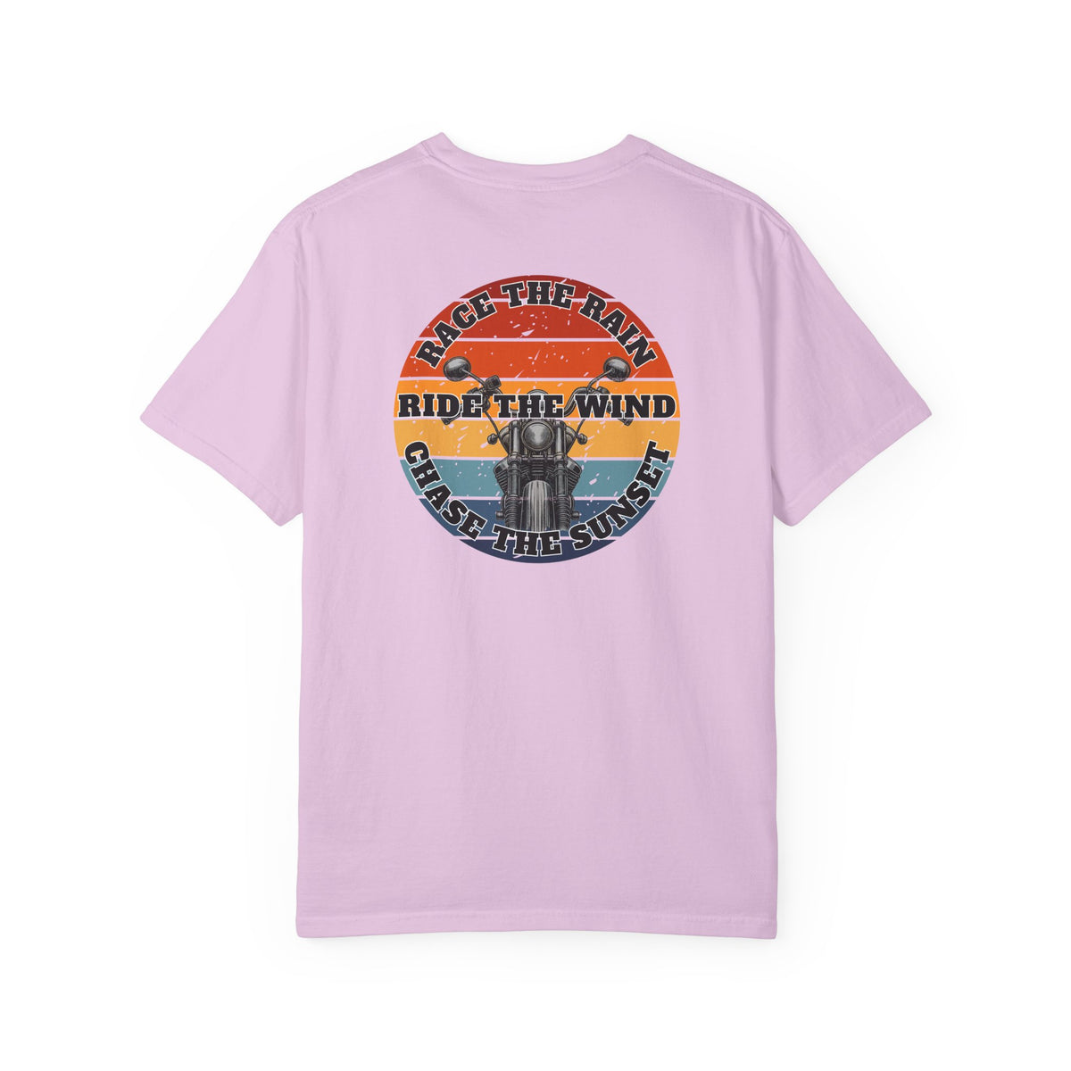 A pink short-sleeve crewneck t-shirt with a retro circular graphic on the chest. The graphic features a motorcycle silhouette and the text 'RACE THE RAIN', 'RIDE THE WIND', and 'CHASE THE SUNSET' in a distressed sunset color palette of orange, yellow, and blue.