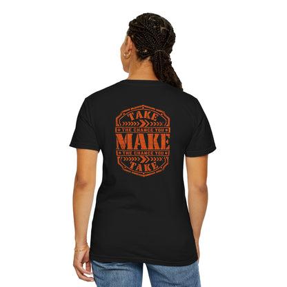 A woman wearing a black short-sleeve t-shirt with a distressed orange graphic on the back reading 'TAKE THE CHANCE YOU MAKE'.