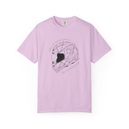 A pink short-sleeve crewneck t-shirt featuring a black line art graphic of a geometric motorcycle helmet in the center, with the text 'When the helmet goes on, the world goes off' curved around it.