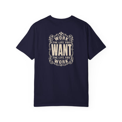 A navy blue short-sleeve crewneck t-shirt with a dark white graphic print on the back. The graphic features the motivational quote 'WORK THE LIFE YOU WANT THE LIFE YOU WORK' in a decorative, vintage-style frame.